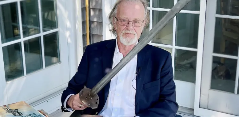 Foto do autor Bernard Cornwell segurando uma espada