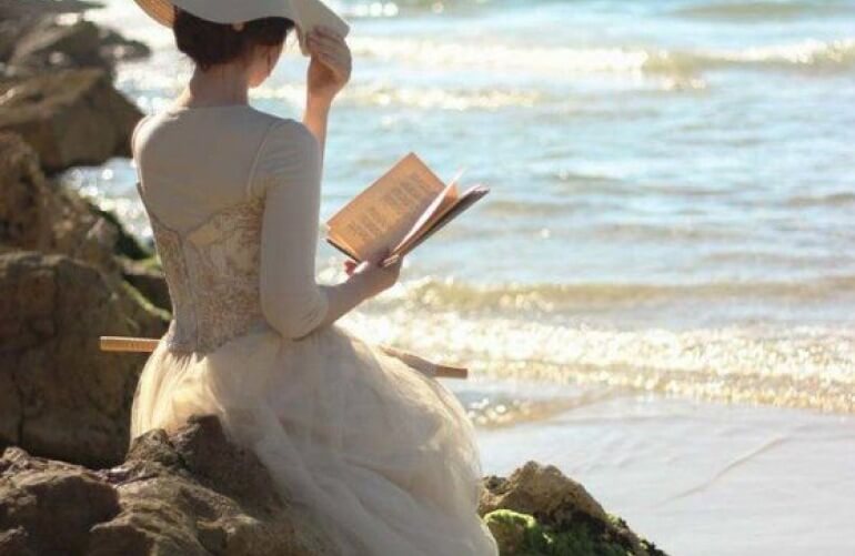 Uma dama lendo um livro em uma praia