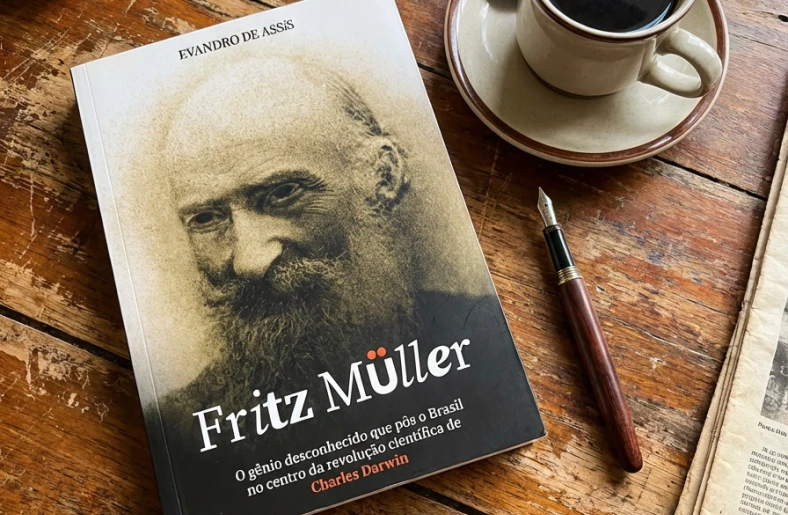 Livro da biografia de Fritz Müller por Evandro de Assis. Ao lado uma caneta tinteiro e um xícara de café
