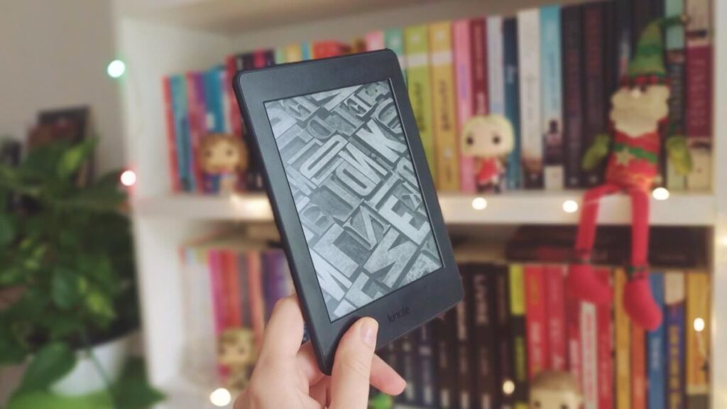 Um leitor kindle com luzes de natal e livros de fundo