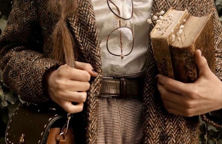 Mulher usando roupas vintage e segurando dois livros antigos