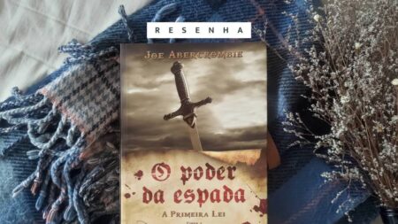 Foto do livro "O Poder da Espada", de Joe Abercrombie. O livro está apoiado sobre um tecido xadrez, com flores secas ao lado. Na parte superior da imagem, faixa branca com a palavra "RESENHA".