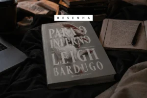 Opinião: Para o Inferno (Trilogia Alex Stern #2) de Leigh Bardugo Livro Para o inferno em cima de uma mesa com iluminação mais sombria e os dizeres "resenha" em cima